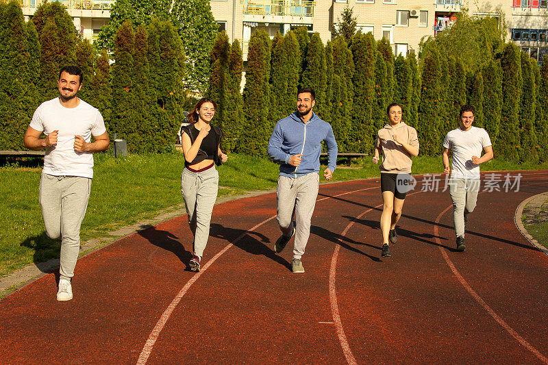 A group of friends running on a track in a public park